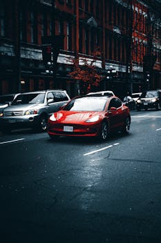 Sleek red electric car driving on an urban street with historic buildings.