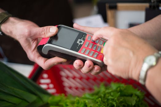 Two people making a cashless payment at a grocery store with a credit card terminal.